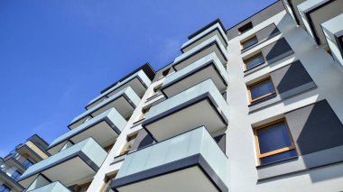 Parlak yüzlü apartman dairesi. Bir sürü kare cam pencere ve balkonu olan modern minimalist mimari.