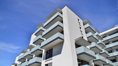 Parlak yüzlü apartman dairesi. Bir sürü kare cam pencere ve balkonu olan modern minimalist mimari.