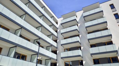 Parlak yüzlü apartman dairesi. Bir sürü kare cam pencere ve balkonu olan modern minimalist mimari.