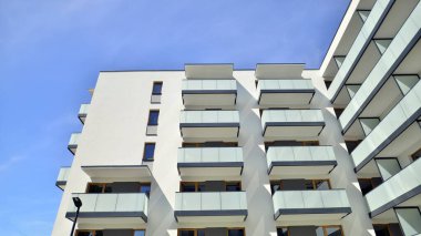 Parlak yüzlü apartman dairesi. Bir sürü kare cam pencere ve balkonu olan modern minimalist mimari.