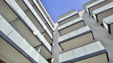 Parlak yüzlü apartman dairesi. Bir sürü kare cam pencere ve balkonu olan modern minimalist mimari.
