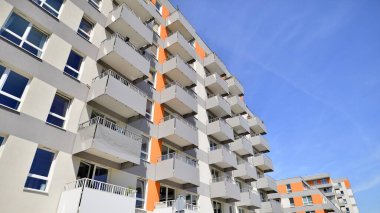 Parlak yüzlü apartman dairesi. Bir sürü kare cam pencere ve balkonu olan modern minimalist mimari.