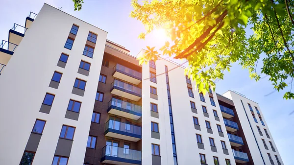 Ecological housing architecture. A modern residential building in the vicinity of trees. Ecology and green living in city, urban environment concept. Modern apartment building and green trees.