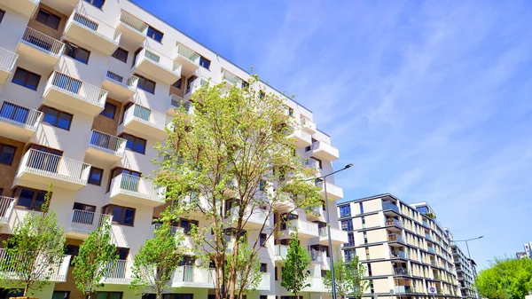 Ecological housing architecture. A modern residential building in the vicinity of trees. Ecology and green living in city, urban environment concept. Modern apartment building and green trees.