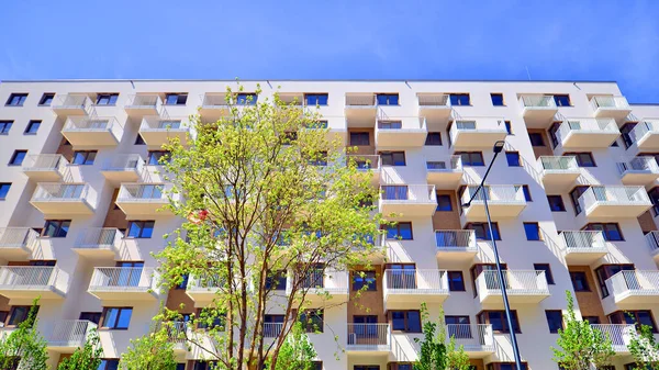 Ecological housing architecture. A modern residential building in the vicinity of trees. Ecology and green living in city, urban environment concept. Modern apartment building and green trees.