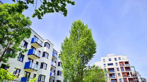 Ecological housing architecture. A modern residential building in the vicinity of trees. Ecology and green living in city, urban environment concept. Modern apartment building and green trees.