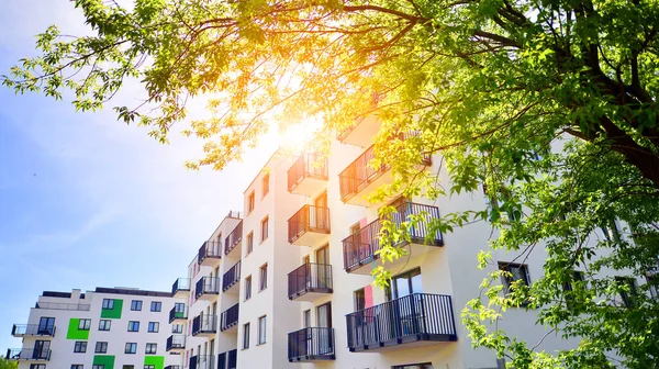 Ecological housing architecture. A modern residential building in the vicinity of trees. Ecology and green living in city, urban environment concept. Modern apartment building and green trees.