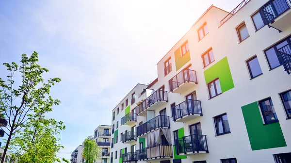 Ecological housing architecture. A modern residential building in the vicinity of trees. Ecology and green living in city, urban environment concept. Modern apartment building and green trees.