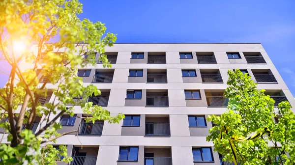 Ecological housing architecture. A modern residential building in the vicinity of trees. Ecology and green living in city, urban environment concept. Modern apartment building and green trees.