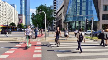 Varşova, Polonya. 23 Haziran 2022. Farklı yaşlarda ve karşıdan karşıya geçen rahat elbiseli insanlar. Şehir caddesi manzarası sakinleri, turistler ve modern binalar.