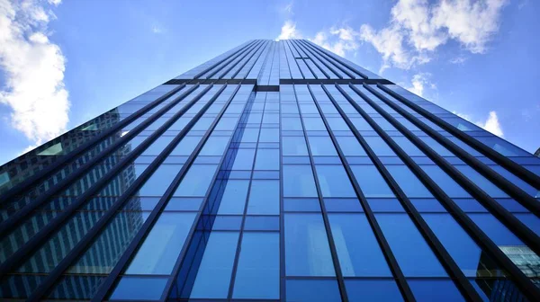 Modern glass facade against blue sky. Bottom view of a  building in the business district. Low angle view of the glass facade of an office building.