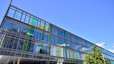 Mavi gökyüzüne karşı modern cam cephe. İş bölgesindeki bir binanın alt manzarası. Bir ofis binasının cam cephesinin alçak açılı görüntüsü.