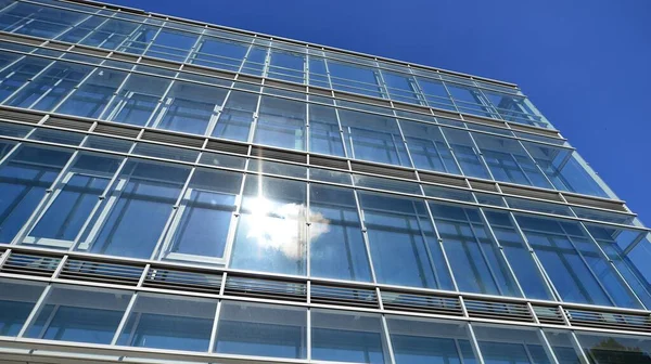 Modern glass facade against blue sky. Bottom view of a  building in the business district. Low angle view of the glass facade of an office building.