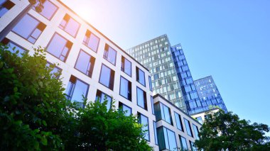 Mavi gökyüzüne karşı modern gökdelenin alt manzarası. Şehir merkezindeki iş binalarına bakıyorum. Ufukta yükselen güneş.