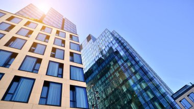 Mavi gökyüzüne karşı modern gökdelenin alt manzarası. Şehir merkezindeki iş binalarına bakıyorum. Ufukta yükselen güneş.