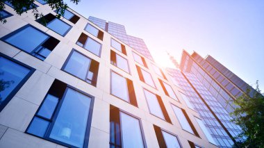 Mavi gökyüzüne karşı modern gökdelenin alt manzarası. Şehir merkezindeki iş binalarına bakıyorum. Ufukta yükselen güneş.