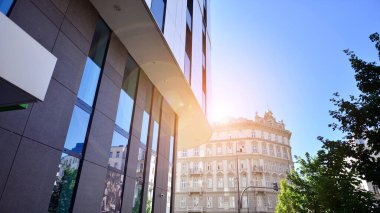 Mavi gökyüzüne karşı modern gökdelenin alt manzarası. Şehir merkezindeki iş binalarına bakıyorum. Ufukta yükselen güneş.