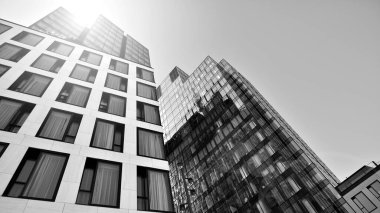 Mavi gökyüzüne karşı modern gökdelenin alt manzarası. Şehir merkezindeki iş binalarına bakıyorum. Ufukta doğan güneş. Siyah ve beyaz.