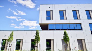 Beyaz alüminyum kompozit panelli ofis binası. Cam ve metalden yapılmış ön duvar. Soyut modern iş mimarisi.