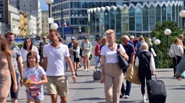 Warsaw, Poland. 10 August 2022. People of different ages and with comfortable clothes crossing the road through. View of a city street with residents, tourists and buildings.