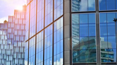 Mavi gökyüzüne karşı modern cam cephe. İş bölgesindeki bir binanın alt manzarası. Bir ofis binasının cam cephesinin alçak açılı görüntüsü.