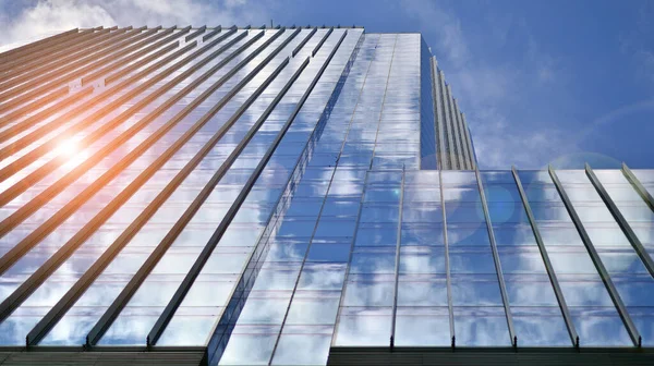 Modern glass facade against blue sky. Bottom view of a  building in the business district. Low angle view of the glass facade of an office building.