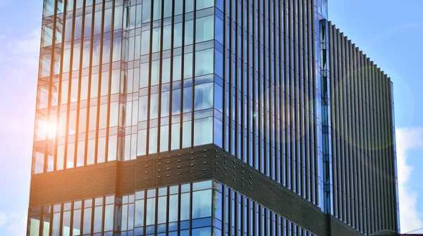 Mavi gökyüzüne karşı modern cam cephe. İş bölgesindeki bir binanın alt manzarası. Bir ofis binasının cam cephesinin alçak açılı görüntüsü.