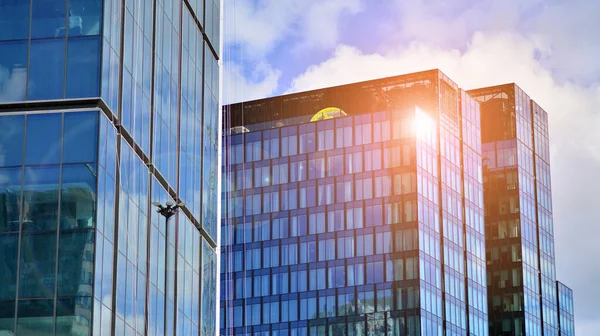 Mavi gökyüzüne karşı modern cam cephe. İş bölgesindeki bir binanın alt manzarası. Bir ofis binasının cam cephesinin alçak açılı görüntüsü.