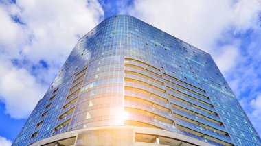 Mavi gökyüzüne karşı modern gökdelenin alt manzarası. Şehir merkezindeki iş binalarına bakıyorum. Ufukta yükselen güneş.