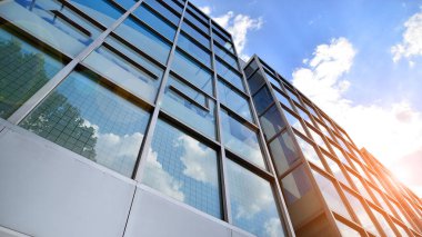Yansıtıcı camlarla kaplı modern bir binanın cam kaplamalı dış cephesinin soyut yakın çekimi. Mimari soyut arkaplan. Cam duvar ve ön cephe ayrıntıları.