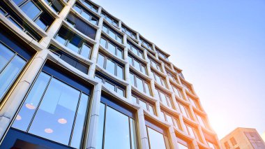 Yansıtıcı camlarla kaplı modern bir binanın cam kaplamalı dış cephesinin soyut yakın çekimi. Mimari soyut arkaplan. Cam duvar ve ön cephe ayrıntıları.
