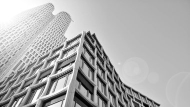 Mavi gökyüzüne karşı modern gökdelenin alt manzarası. Şehir merkezindeki iş binasına bakıyorum. Siyah ve beyaz.