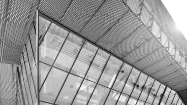 Yansıtıcı camlarla kaplı modern bir binanın cam kaplamalı dış cephesinin soyut yakın çekimi. Mimari soyut arkaplan. Cam duvar ve ön cephe ekibi. Siyah ve beyaz.