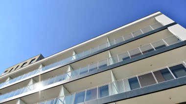 Modern lüks konut dairesi. Güneşli bir günde modern apartman binası. Mavi gökyüzü olan bir apartman. Modern bir apartmanın cephesi.