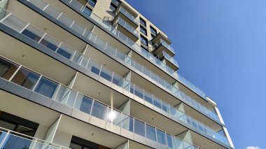 Modern lüks konut dairesi. Güneşli bir günde modern apartman binası. Mavi gökyüzü olan bir apartman. Modern bir apartmanın cephesi.