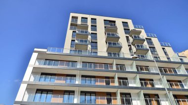 Modern lüks konut dairesi. Güneşli bir günde modern apartman binası. Mavi gökyüzü olan bir apartman. Modern bir apartmanın cephesi.