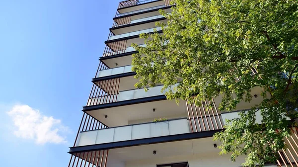 Modern residential building with new apartments in a green residential area. Eco architecture. Green tree and new apartment building. The harmony of nature and modernity.