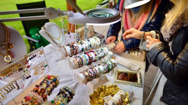 Güzel bir kadın, değerli taşlardan bilezikler yapmaya çalışıyor..