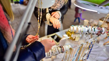 Güzel bir kadın, değerli taşlardan bilezikler yapmaya çalışıyor..