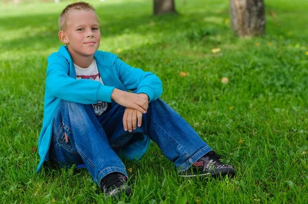 Giovane ragazzo seduto all'aperto — Foto Stock