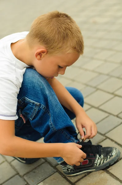 Хлопчик зав'язує шнурки Стокове Фото