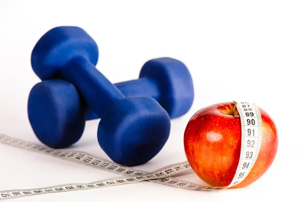 Blue dumbbells and red apple with measure tape — Stock Photo, Image