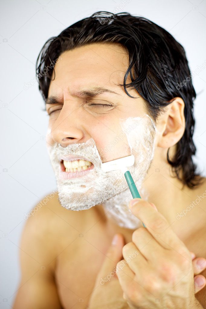 Young man hurting himself shaving with blade