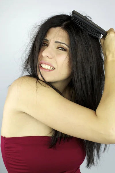 Beautiful woman trying to brush her messy hair — Stock Photo, Image