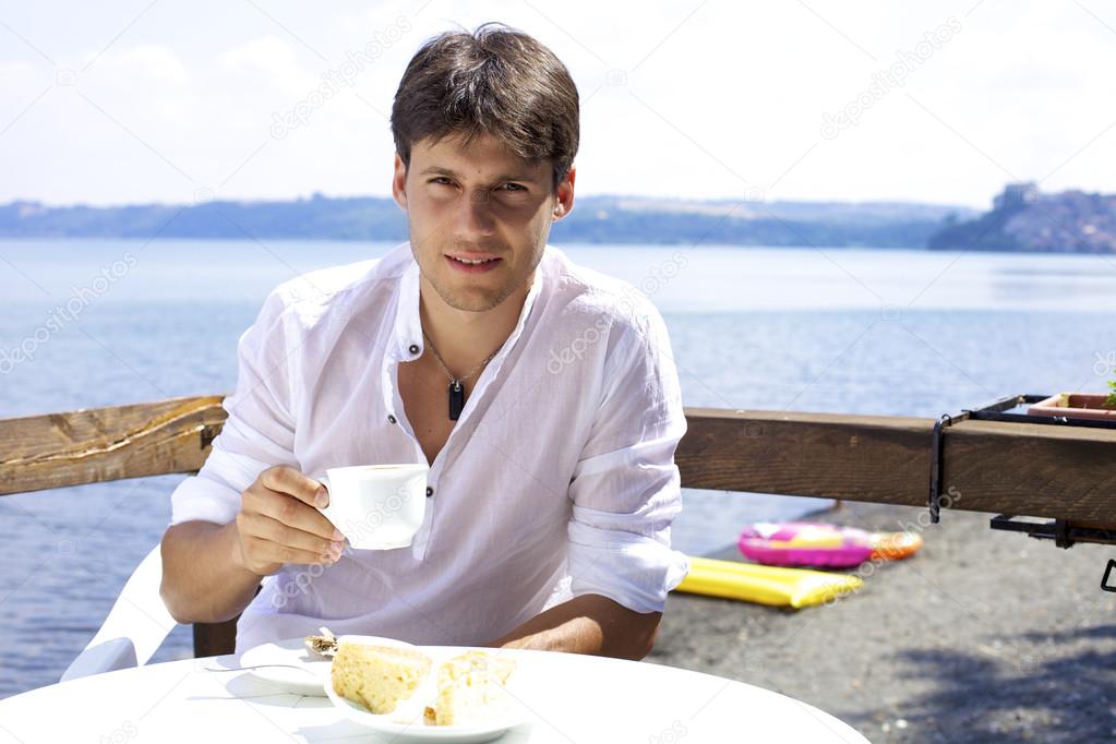 Handsome man having breakfast in front of lake in Italy