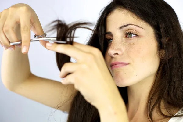 Serious beautiful woman cutting split ends hair — Stock Photo, Image