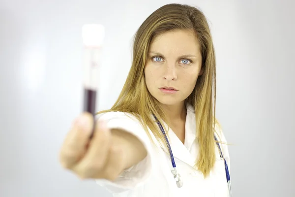 Médico femenino serio de buen aspecto con muestra de sangre en la mano buscando — Foto de Stock