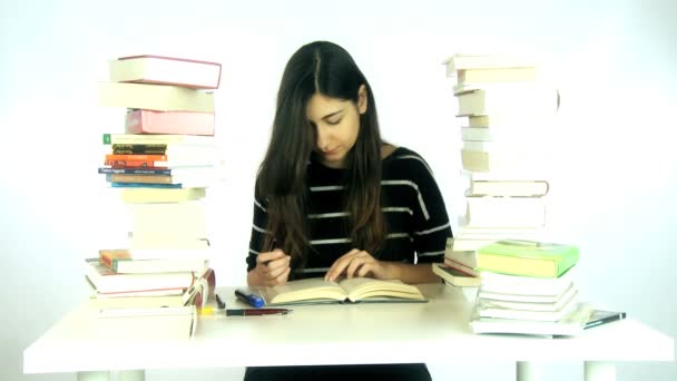Ung kvinnlig student som läser bok omgiven av böcker — Stockvideo