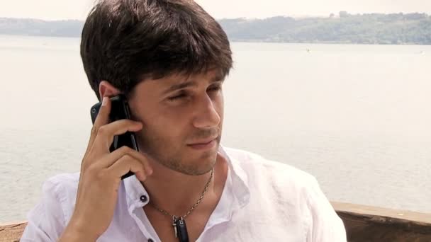 Щасливий красивий чоловік розмовляє по телефону на озері — стокове відео