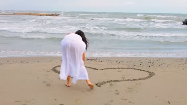 Mujer pintando amor signo en la arena — Vídeo de stock